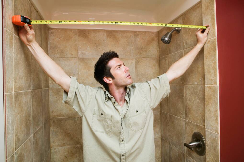 Young man measuring the width of the bathroom with a tape measure Home Inspirations wrapsDIYBudget busters for renovators