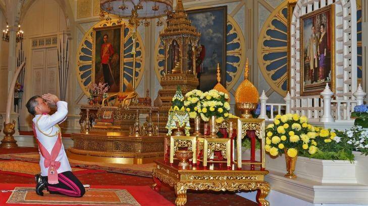 His Majesty King Maha Vajiralongkorn Bodindradebayavarangkun, or Rama X, kneels under a portrait of his late father at the Grand Palace in Bangkok, on Thursday. Photo: Royal Household/AP