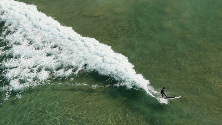 A surfer rides a wave at Manly Beach, seen from a blimp. Photo: Cameron Spencer, Getty
