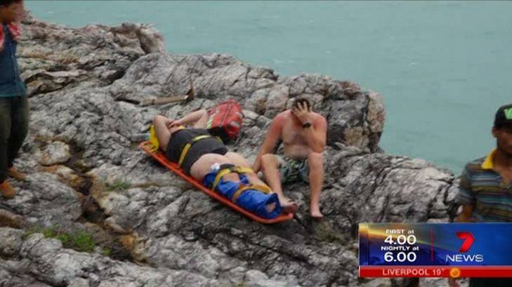 Tourists, including a woman who appears to have an injured right leg, sit on rocks waiting for assistance. Photo: Seven News