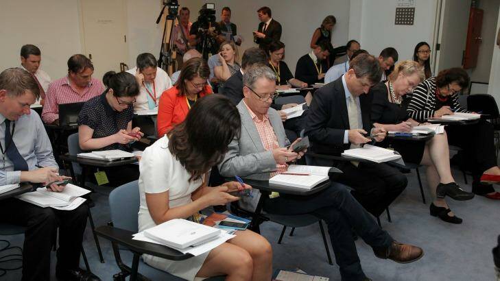 Journalists read their copies of the MYEFO ahead of the update from the government. Photo: Alex Ellinghausen